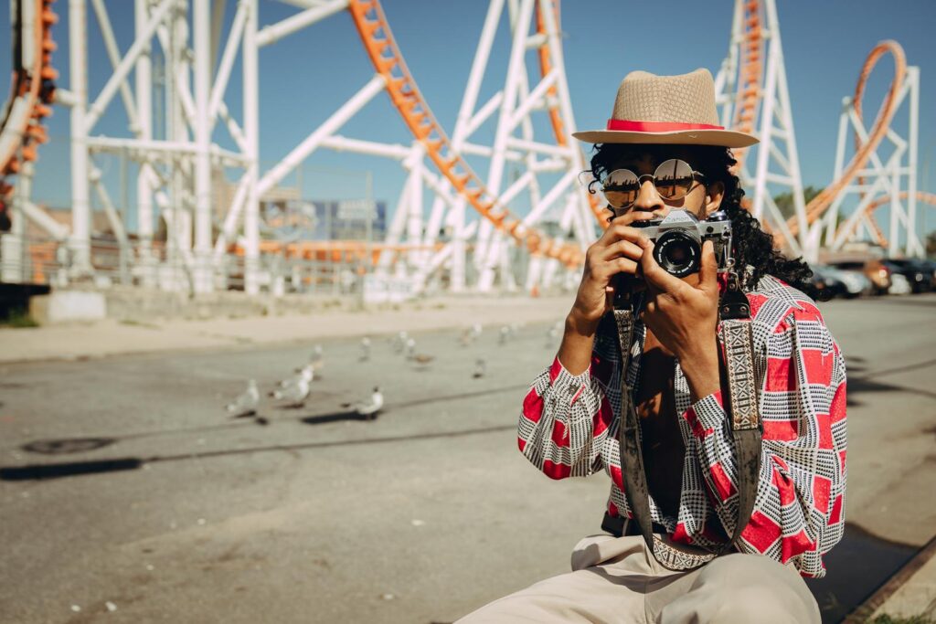 Stylish photographer capturing moments at a New York amusement park under the bright daylight.