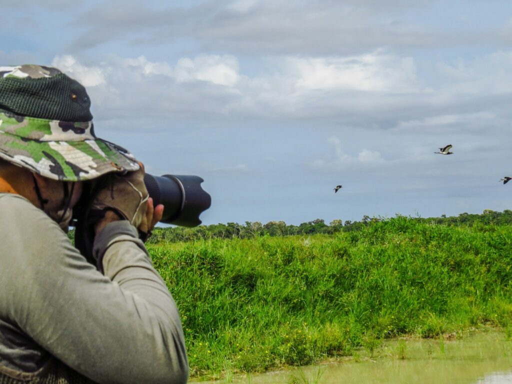 A person wearing a camouflage hat and long sleeves is likely engaged in birdwatching.