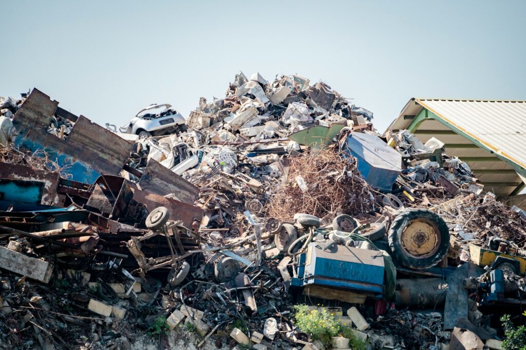 Chaotic pile of scrap metal and discarded items under a clear sky.