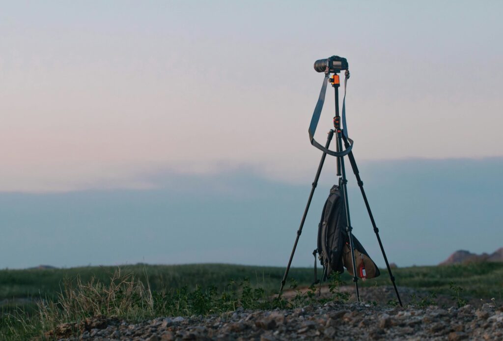 A camera on a tripod with a bag hangs below, likely for birding.