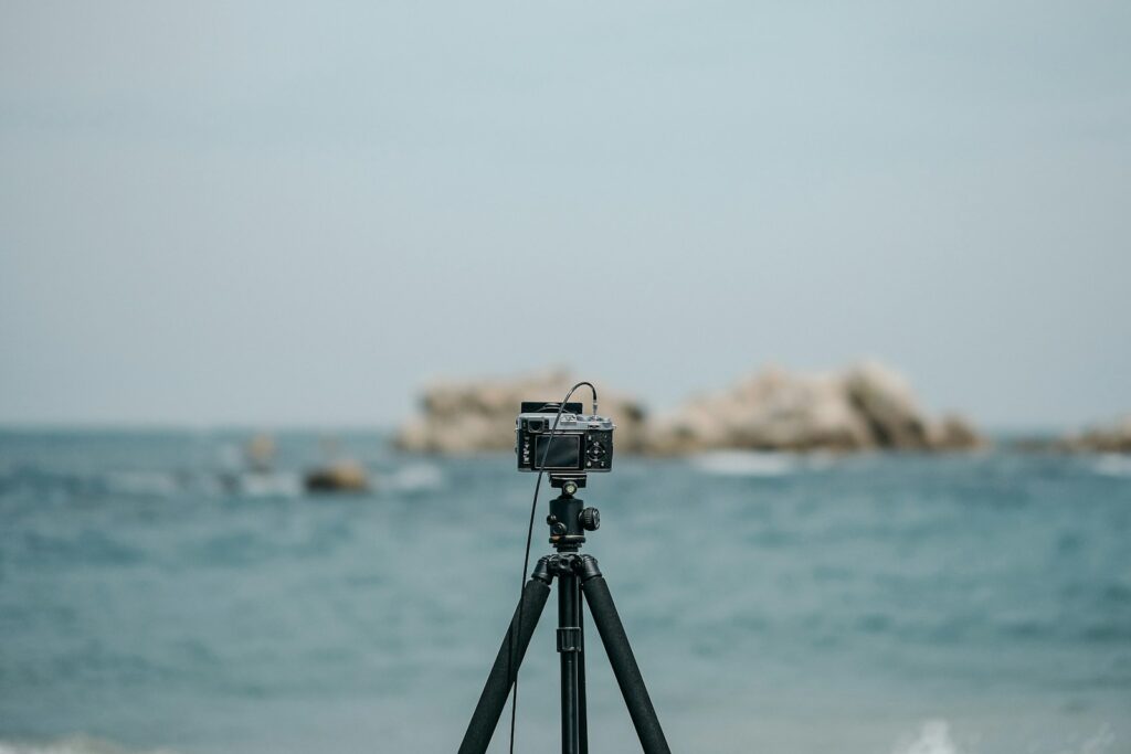 A camera is mounted on a tripod facing the sea, for birding photography.