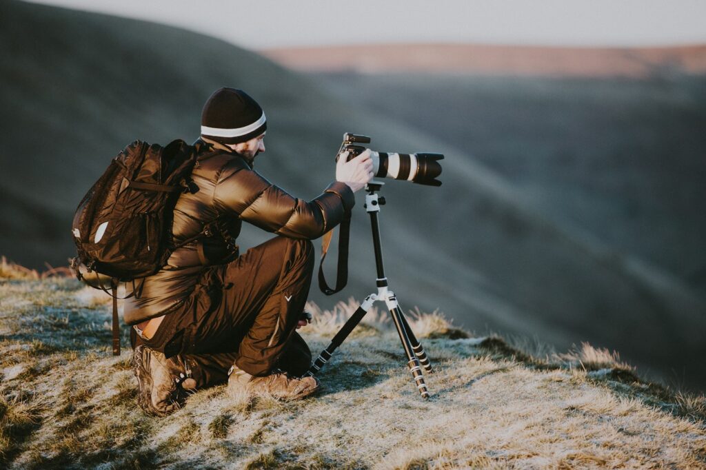 A photographer with a large lens on a tripod and a backpack appears to be setting up for birding.