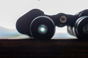 A pair of black Oberwerk Mariner 8x40 binoculars rests on a surface, showing the lens reflection.