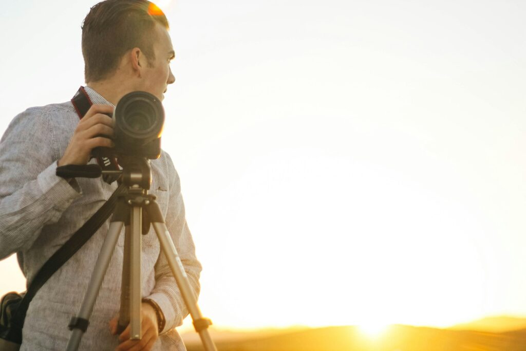 A person holds a camera on a tripod, preparing for birding photography.
