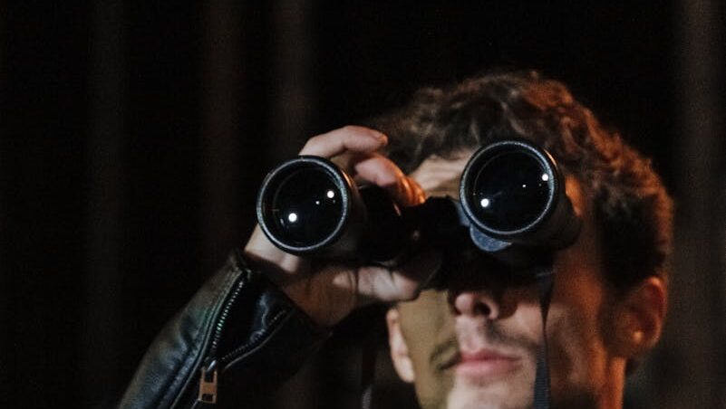 Man using binoculars to observe surroundings at night