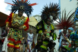 Colorful tribal dancers in traditional costumes, performing in a lively outdoor parade.