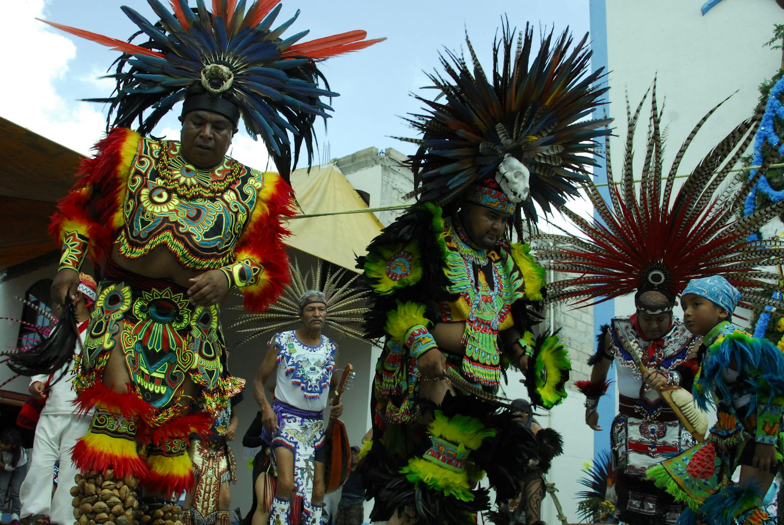 Colorful tribal dancers in traditional costumes, performing in a lively outdoor parade.