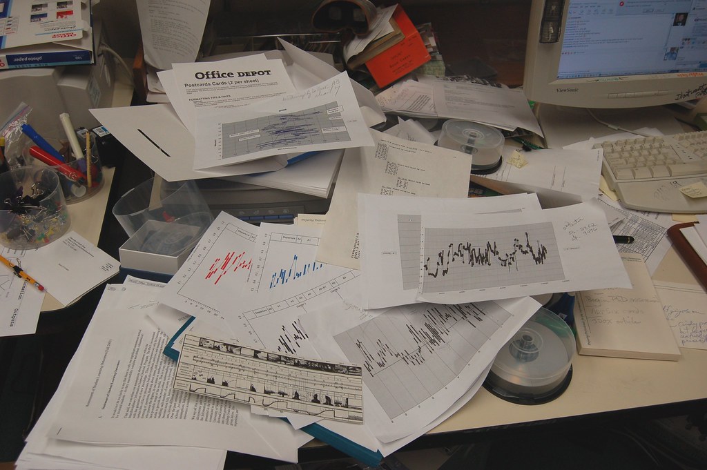 A cluttered desk with papers showing various data graphs.