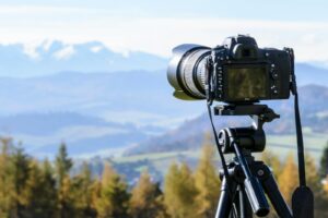 A DSLR camera on tripod capturing a stunning mountain view on a clear day.