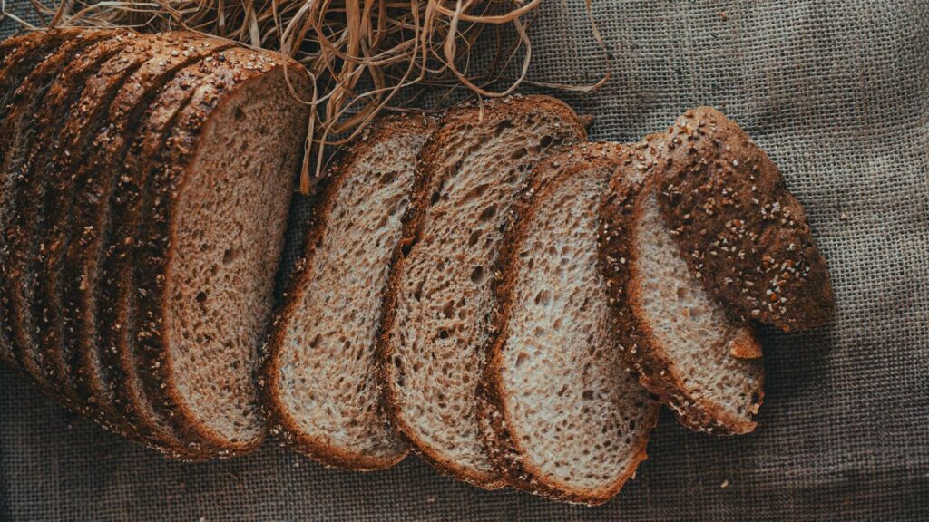 Sliced whole wheat bread loaf resting on burlap cloth