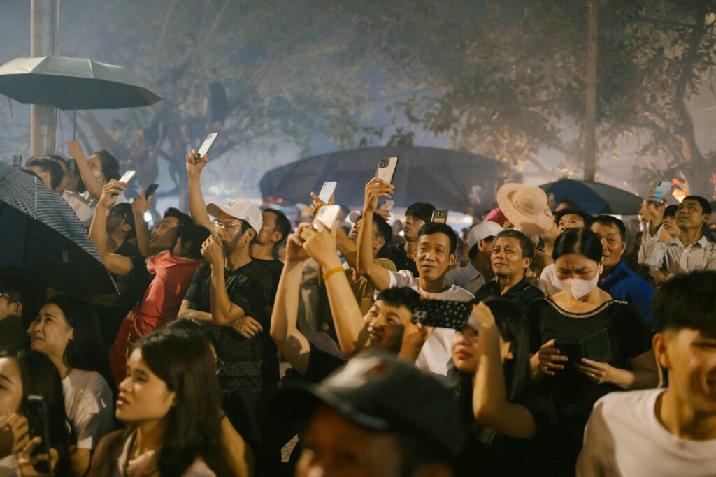 A large crowd of people are holding up their phones, appearing to take pictures.