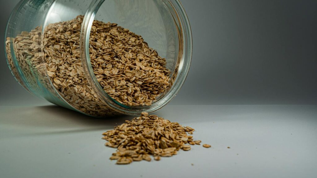 A glass jar spilling rolled oats