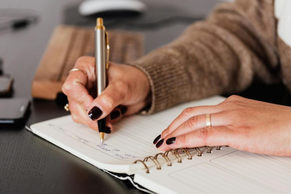 A women write in a spiral-bound notebook.