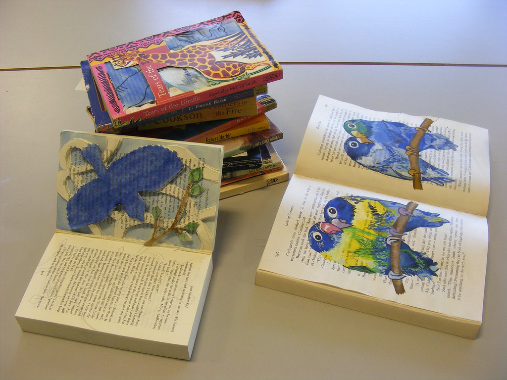 Two colorful lovebirds perched on a book page.