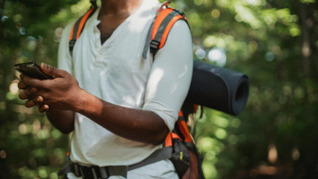 Man checking smartphone in forest during summer hiking trip