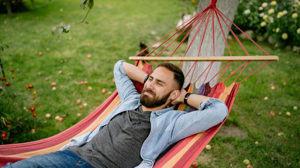 Man with beard relaxing while lying in garden hammock