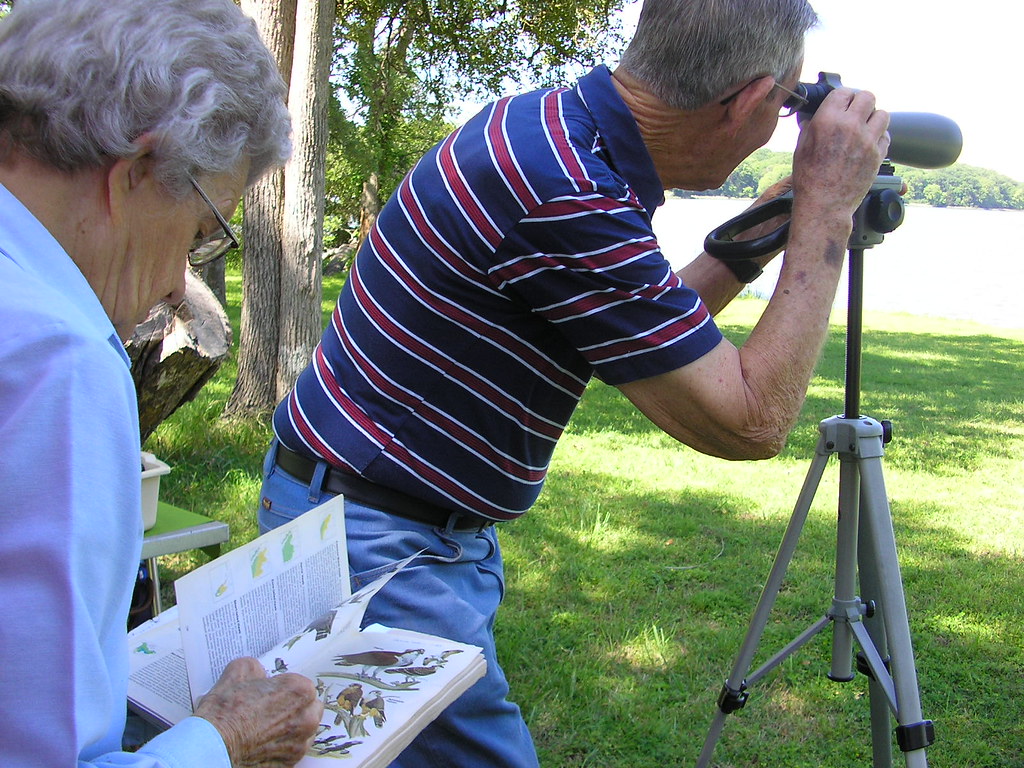 A man and woman spot birds with a telescope.