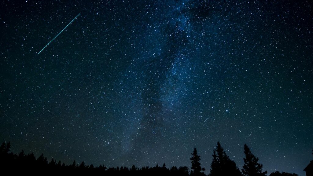 Starry night sky with a shooting star streaking across the dark sky