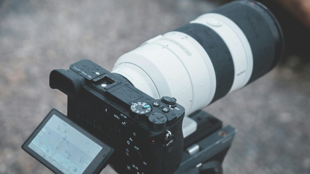 camera with a large telephoto zoom lens attached is mounted on a tripod.