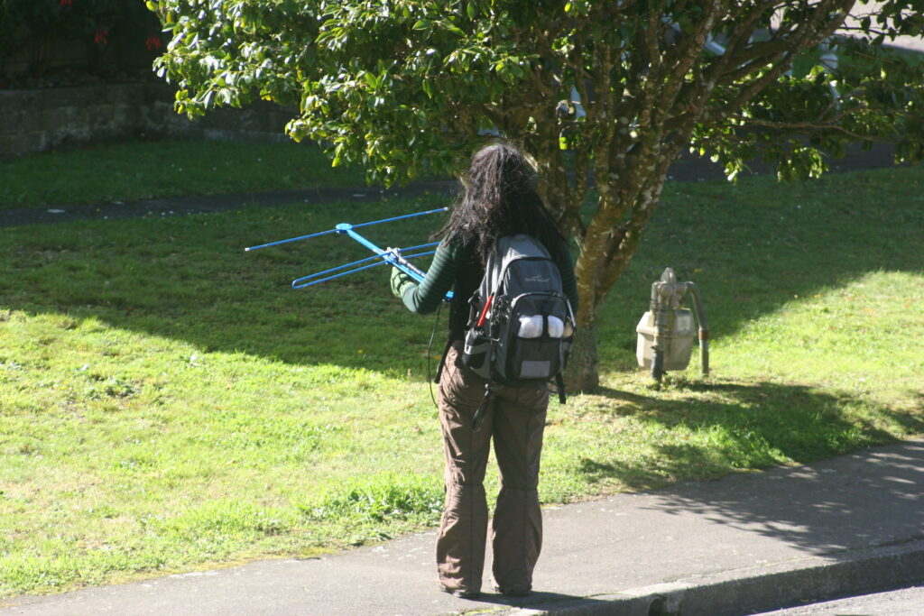 A person with a backpack holds a bird tracking telemetry receiver.