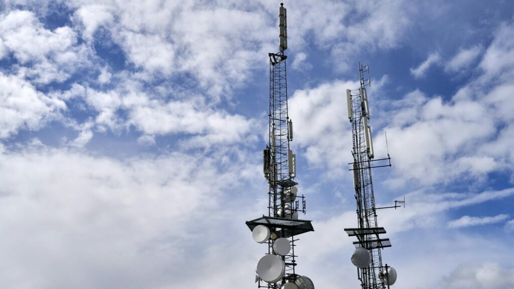 Two cell towers standing tall against a clear blue sky