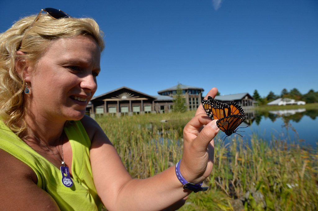 A woman holds a Monarch butterfly on her finger.