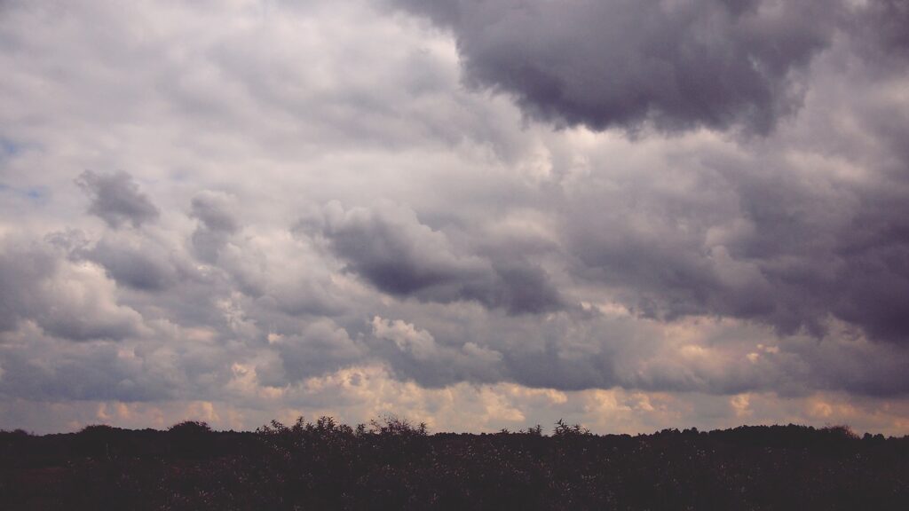 White clouds gathering over open field before approaching storm