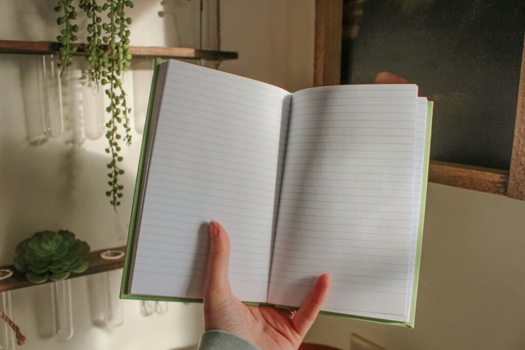 An open notebook is held in front of the camera.