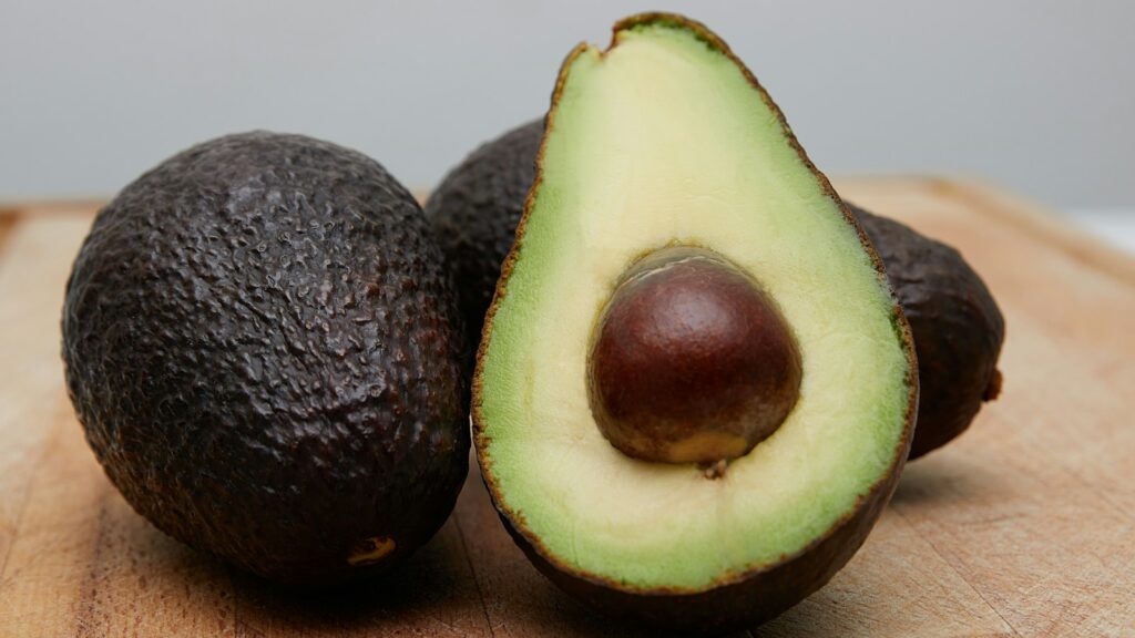 Fresh avocados placed on top of a wooden table