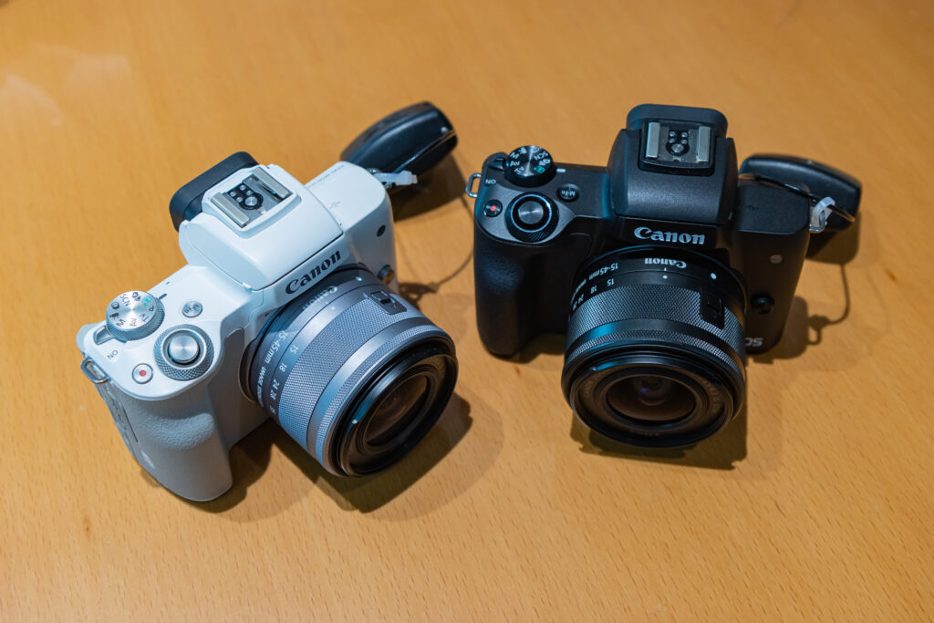 Two Canon EOS M50 cameras are placed on a wooden surface.