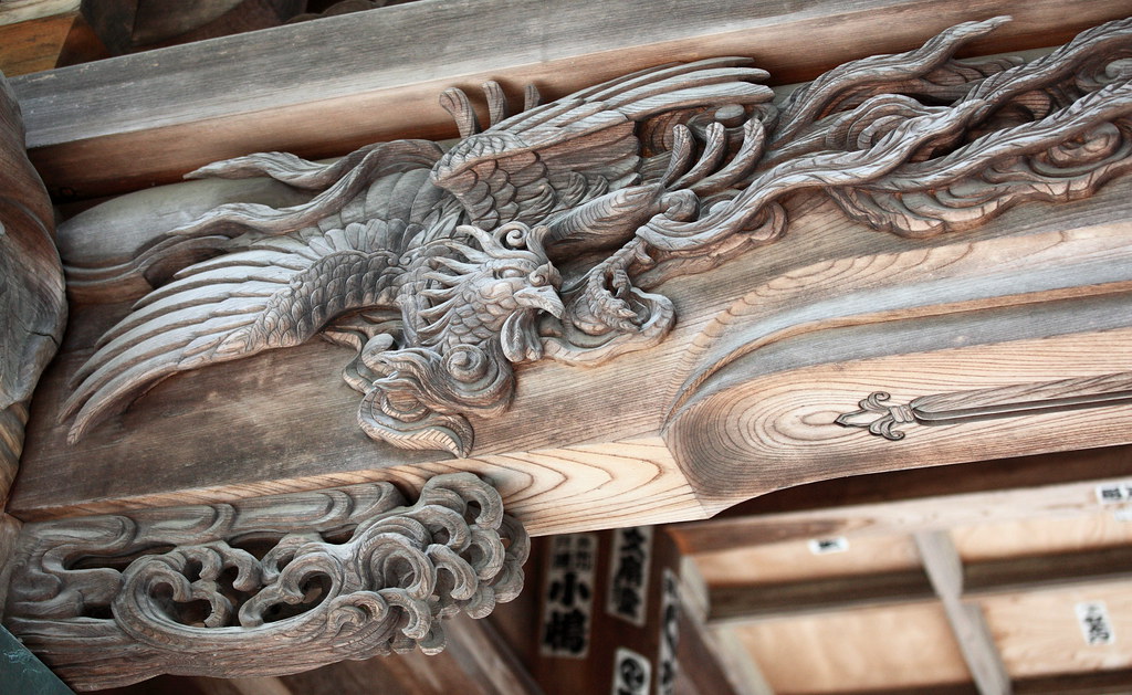 A detailed wooden carving depicts a Chinese phoenix.