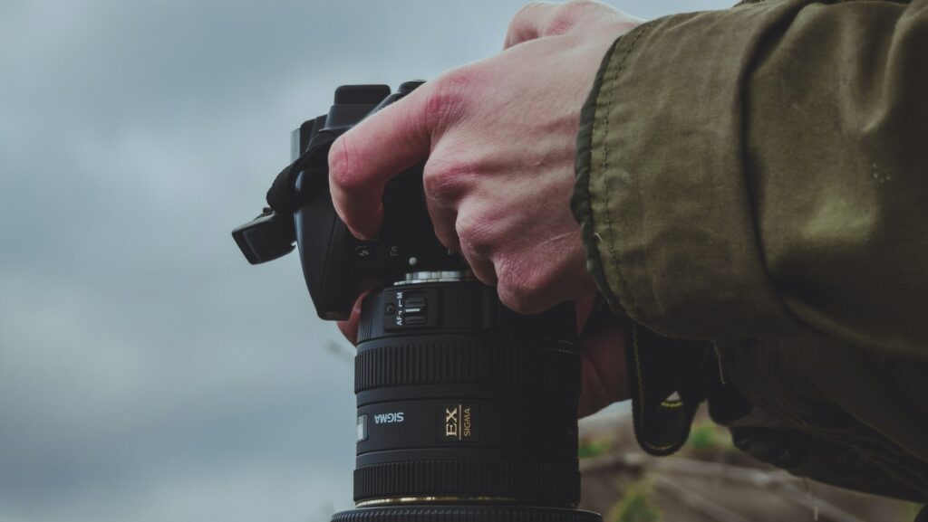 Man holding DSLR camera while adjusting settings