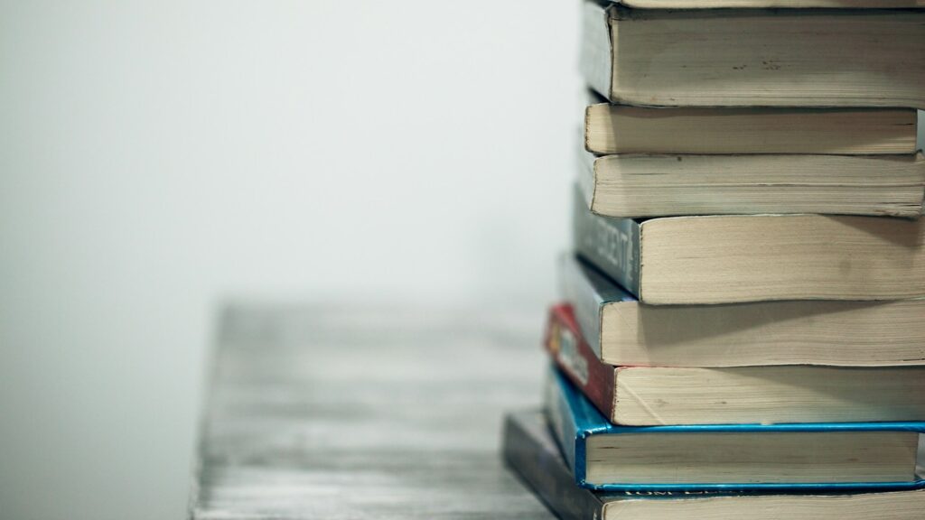 Stack of assorted books on wooden table