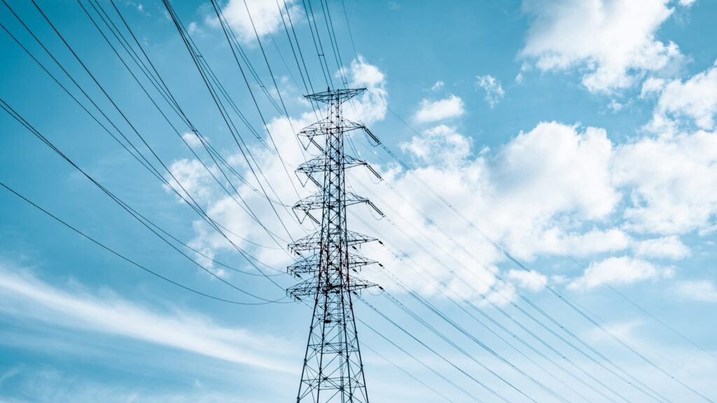Tall electrical tower with power lines against blue sky