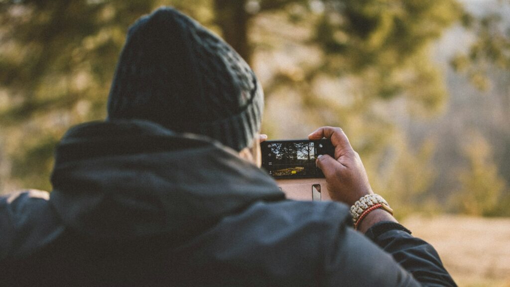 person taking a photo with a smartphone in forest