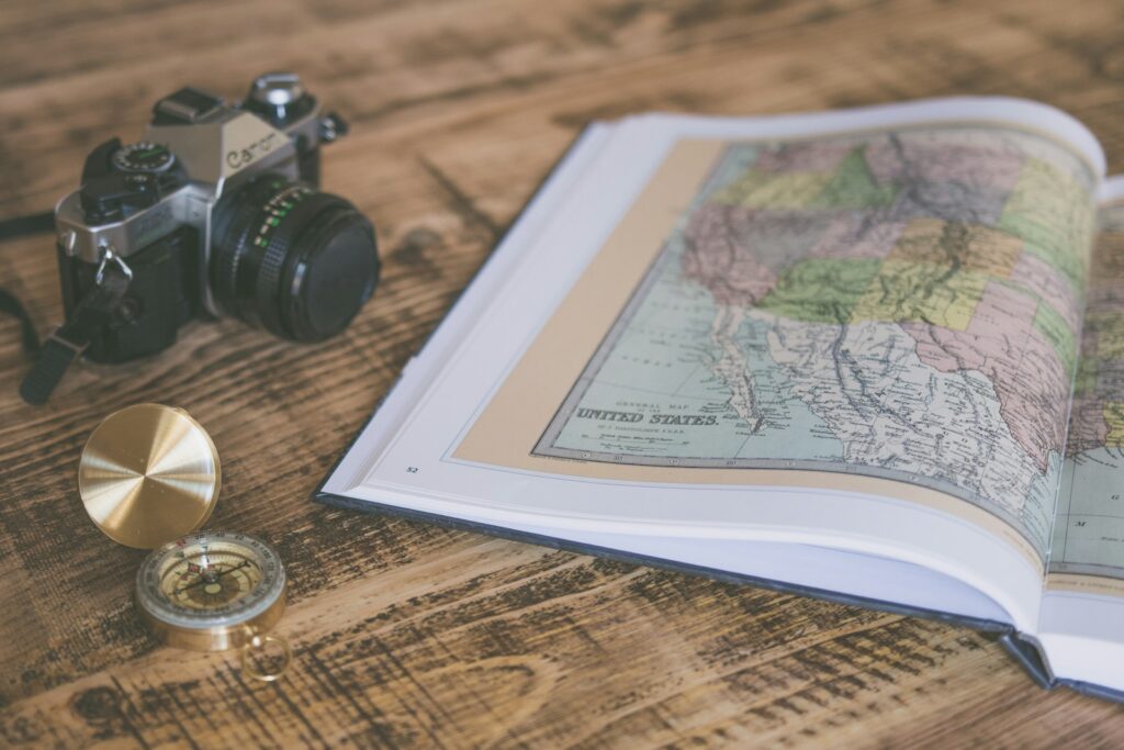 A camera and a map are placed on a wooden table.