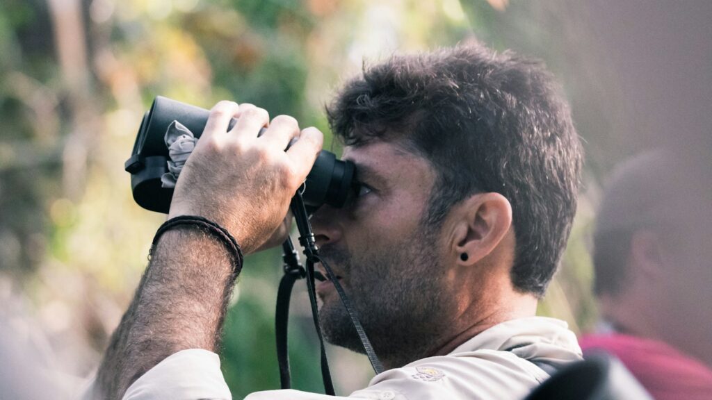 man using black binoculars at daytime