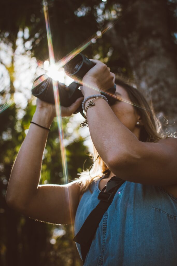 Birdwatcher holding binoculars, standing under a tree