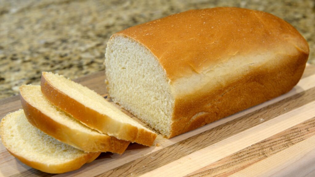 Sliced white bread loaf on wooden serving board