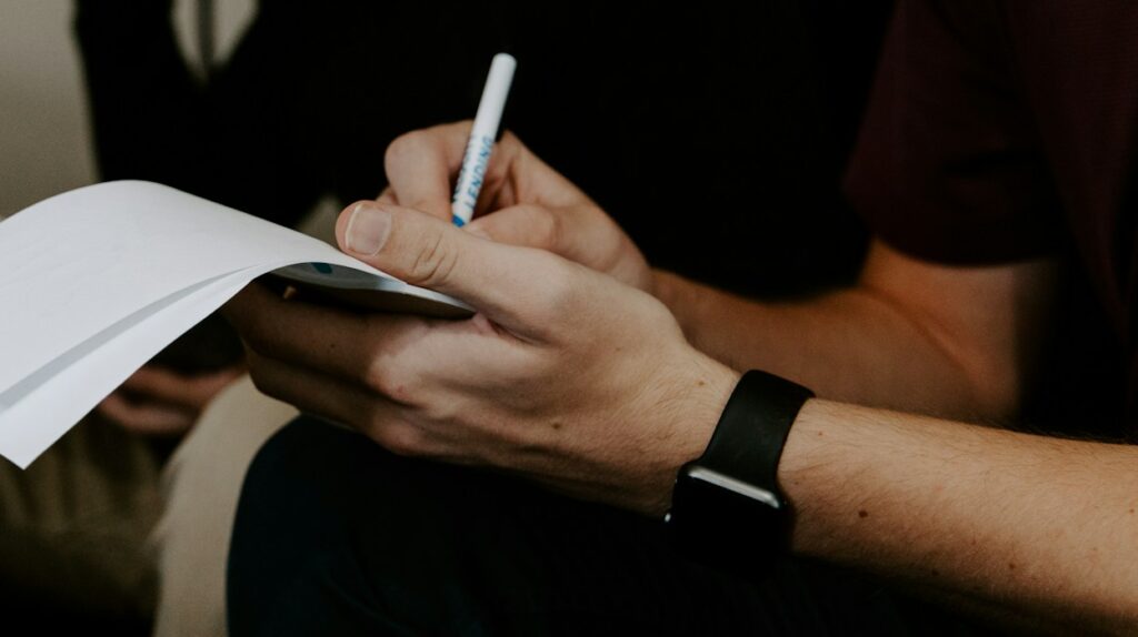 Man sitting and writing notes thoughts in a journal
