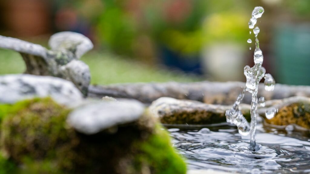 Close-up shot of a stone fountain with flowing water in a garden