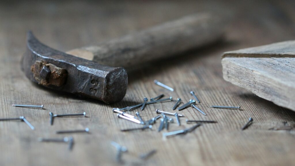 Hammer and nails resting on a wooden surface