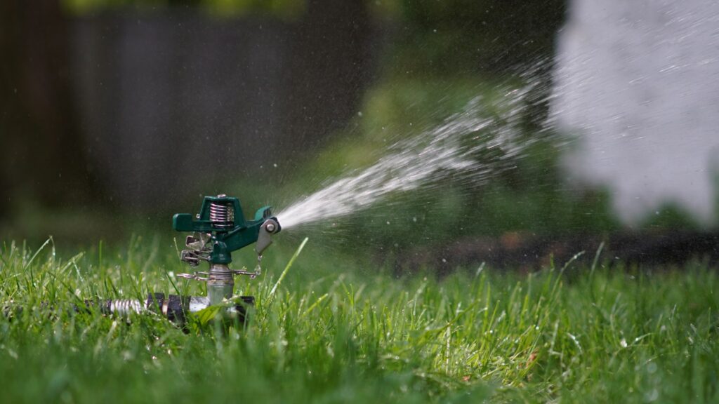 Garden sprinkler spraying water over a lawn
