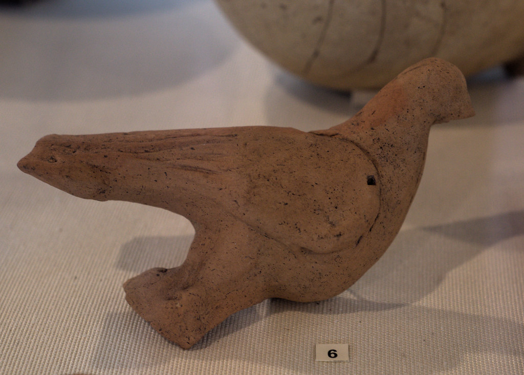 A reddish-brown, unglazed terracotta dove bird sculpture is displayed.