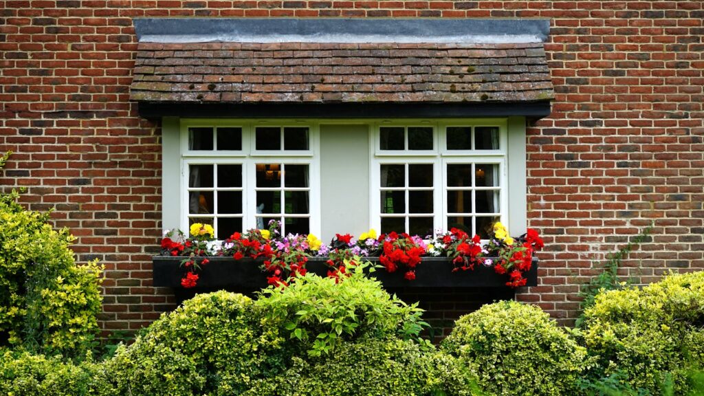 Charming brick cottage window overlooking lush garden