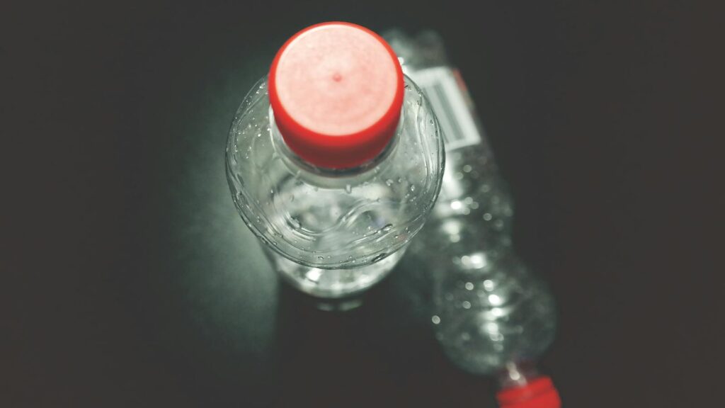 Top view of two clear plastic bottles with red caps