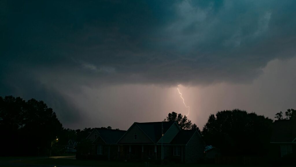 Dark storm clouds with lightning striking over a residential neighborhood