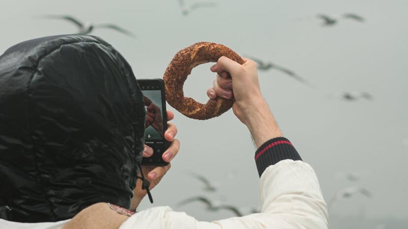 Woman holding a bagel, positioning for a creative photo with seagull in frame