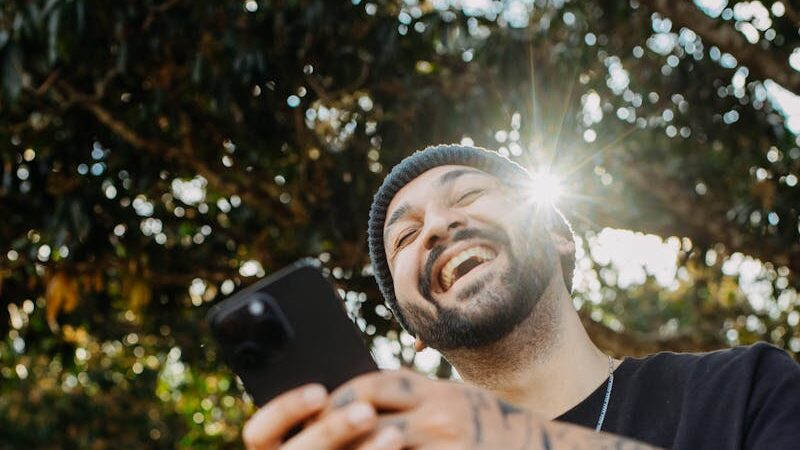 Man laughing while looking at his smartphone screen