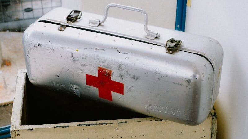 A metal first aid kit on top of a box
